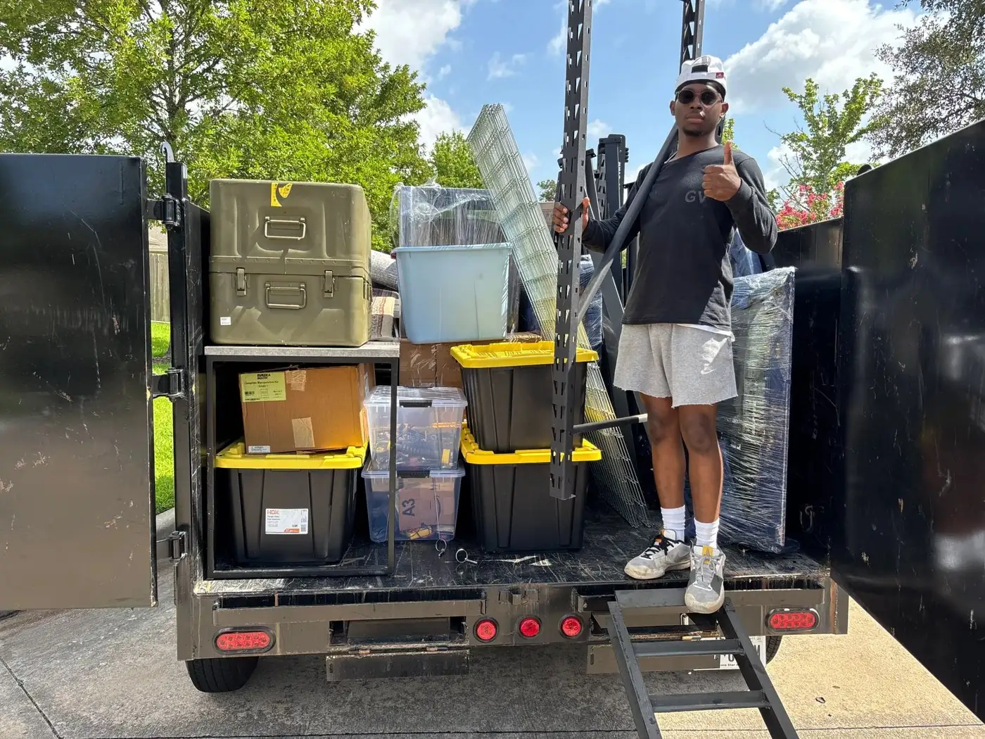 A 2 Florida Boys trailer loaded neatly with bins, boxes and furniture on a driveway